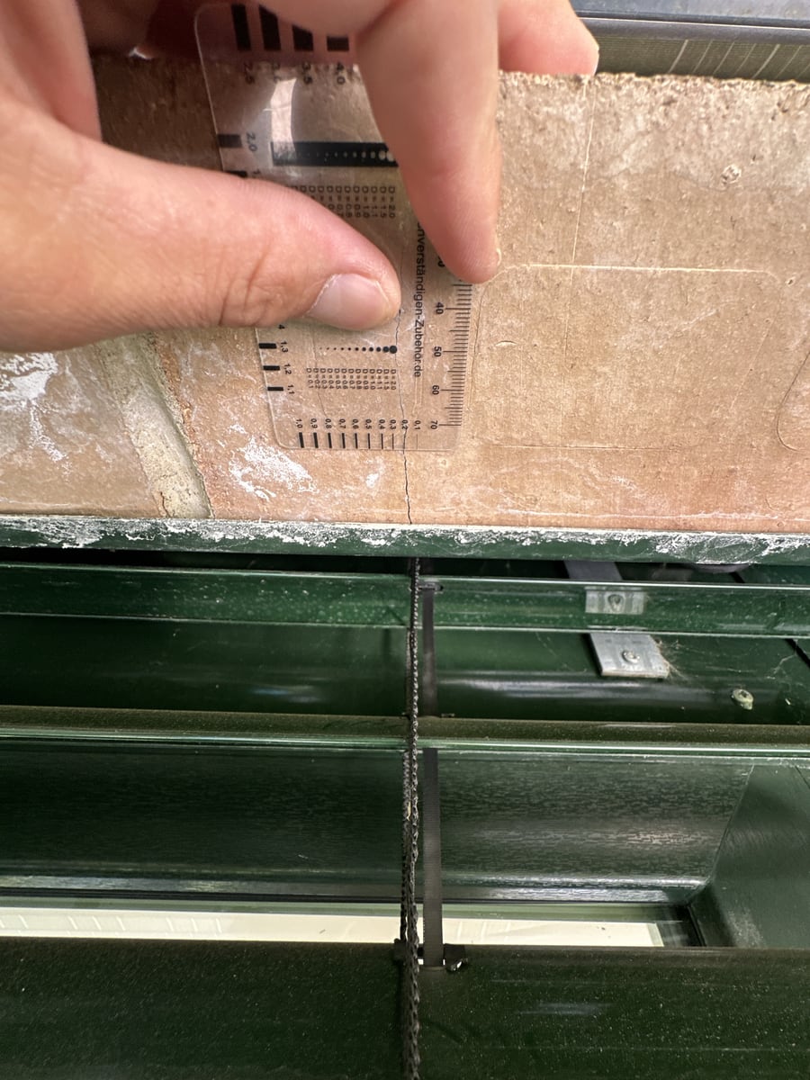 Rissbreitenlupe auf der Oberseite eines Fenstersturzes, der Riss läuft quer über den Stein
